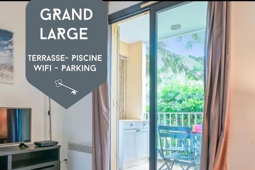 a room with a sliding glass door with the words grand large transfer pressure wifi parking at Joli T2 - domaine de la Coudouliere - Piscine in Six-Fours-les-Plages