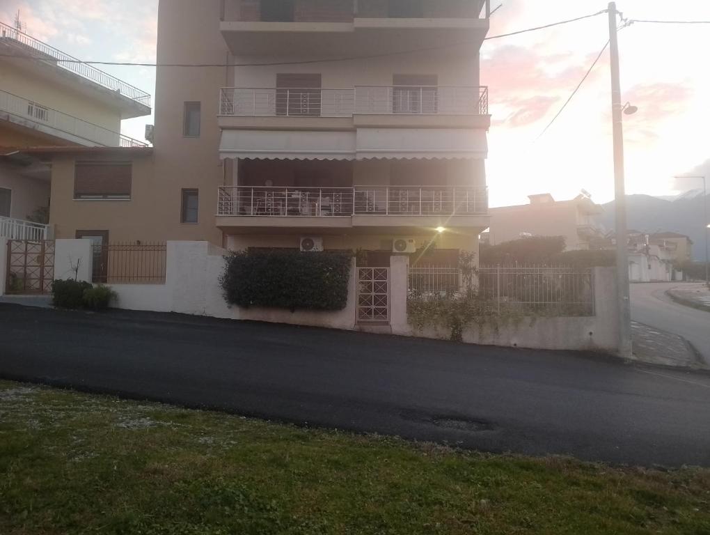 a building on a street with the sunset in the background at Corner house in Leptokaria