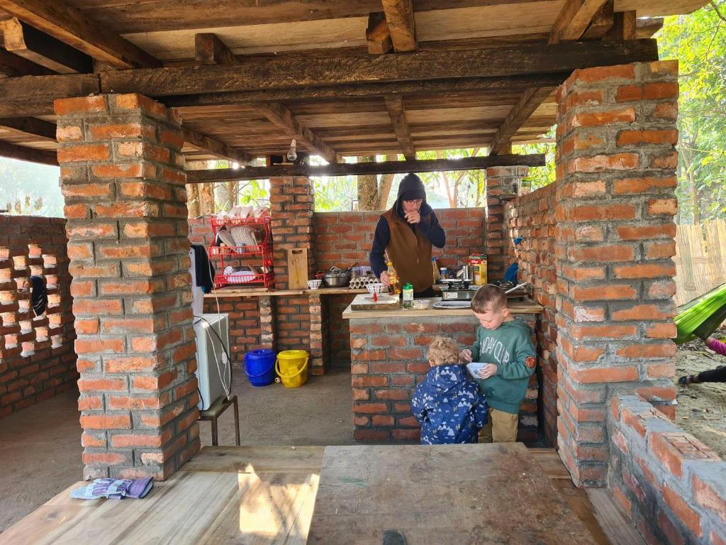 a woman and two children standing in a brick kitchen at Jaryum homestay in Dijmur