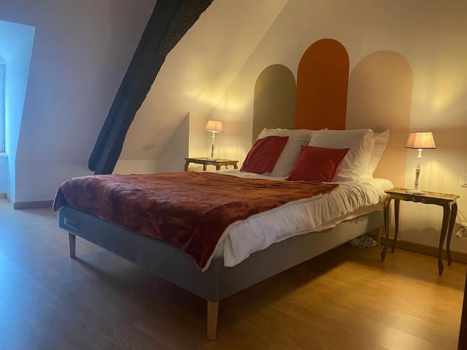 ein Schlafzimmer mit einem großen Bett mit roten Kissen in der Unterkunft Appartement, cité médiévale in Laon
