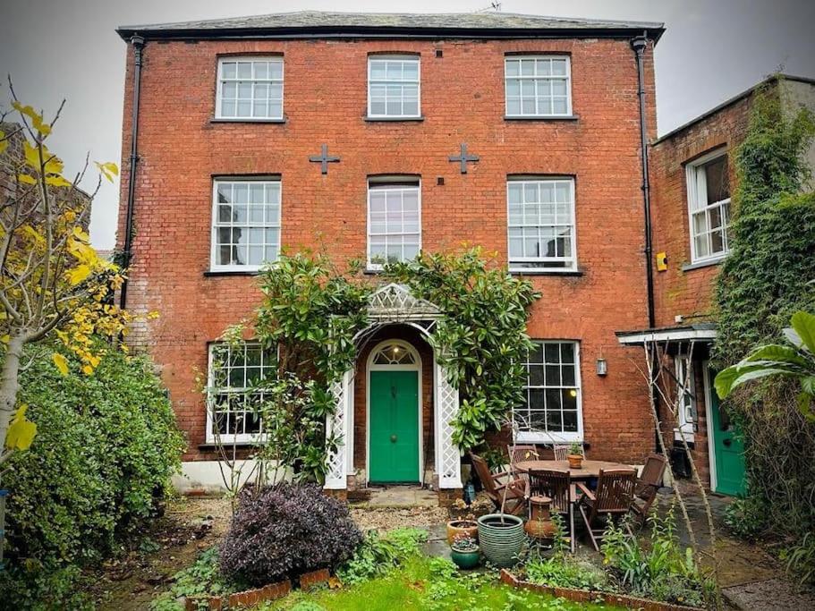 a brick house with a green door and a table at Large Georgian house in heart of Exeter in Exeter