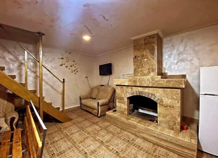 a living room with a stone fireplace and a chair at Rent Hause in Vedi