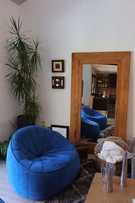 a living room with a blue chair and a mirror at Un paradis avec piscine au cœur du village in Cassis