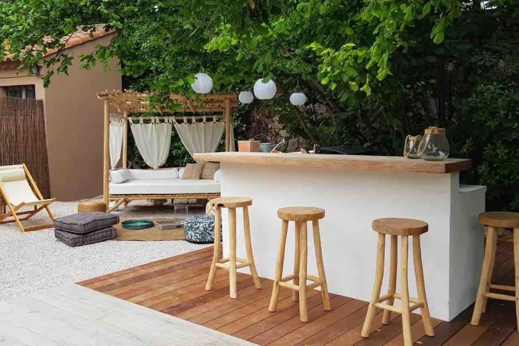 a patio with a bar and some stools at Un paradis avec piscine au cœur du village in Cassis