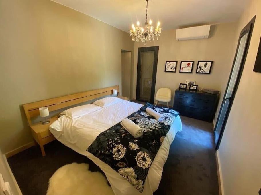 a bedroom with a bed and a chandelier at Un paradis avec piscine au cœur du village in Cassis