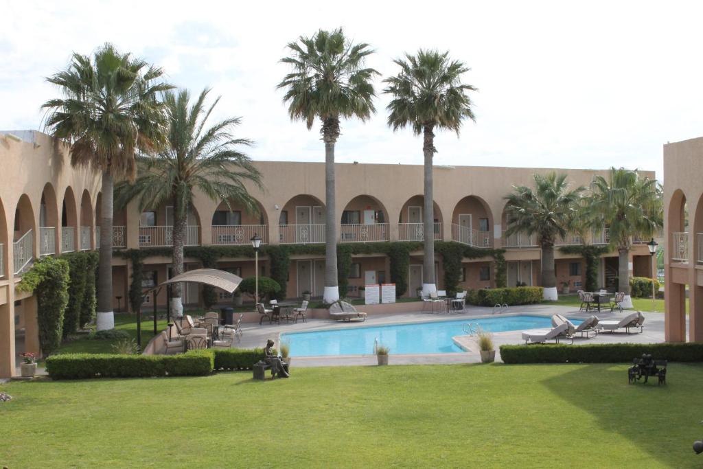 un complejo con piscina y palmeras en Hotel Santa Fe, en Camargo