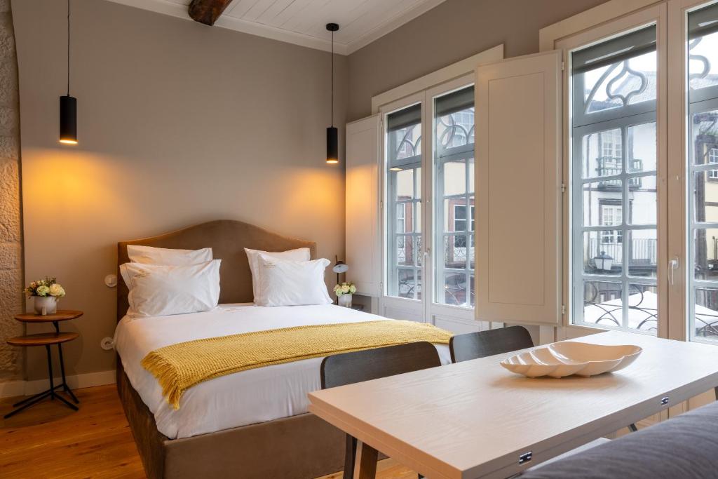 sypialnia z łóżkiem, stołem i oknami w obiekcie Aparthotel Largo da Oliveira w mieście Guimarães