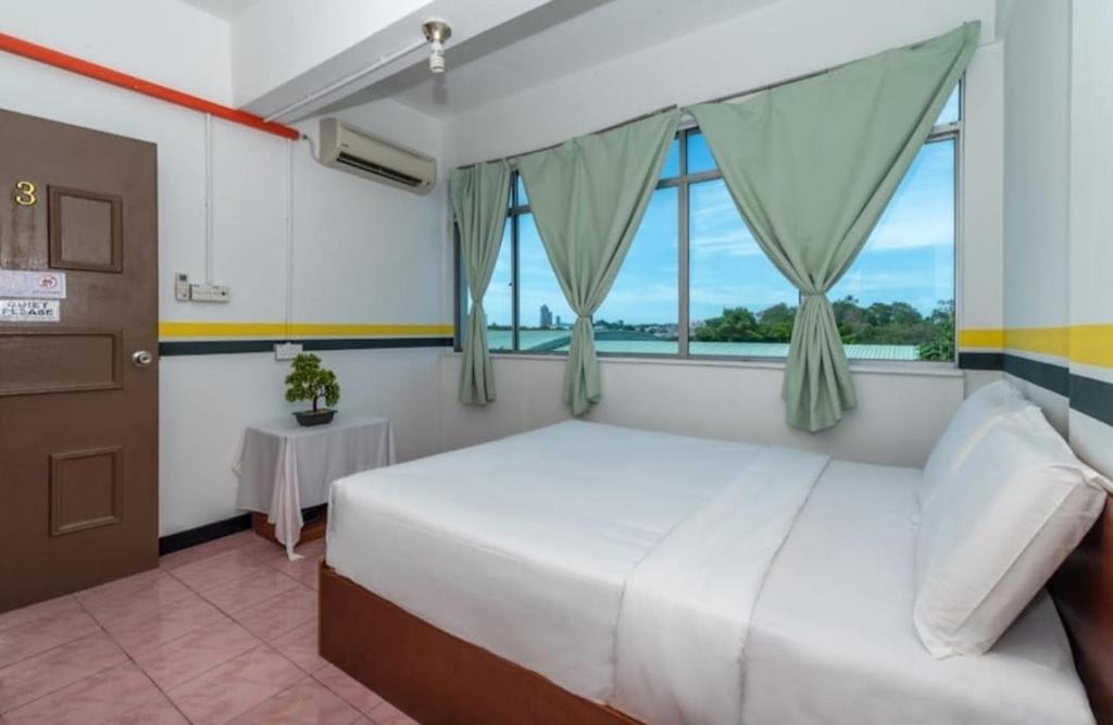 um quarto com uma cama grande e uma janela em Sutera Inn Inanam em Kota Kinabalu