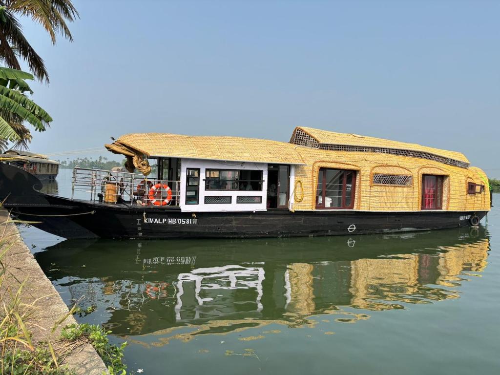 a yellow house boat sitting in the water at PUNNAMADAKKARAN CRUISE in Alleppey