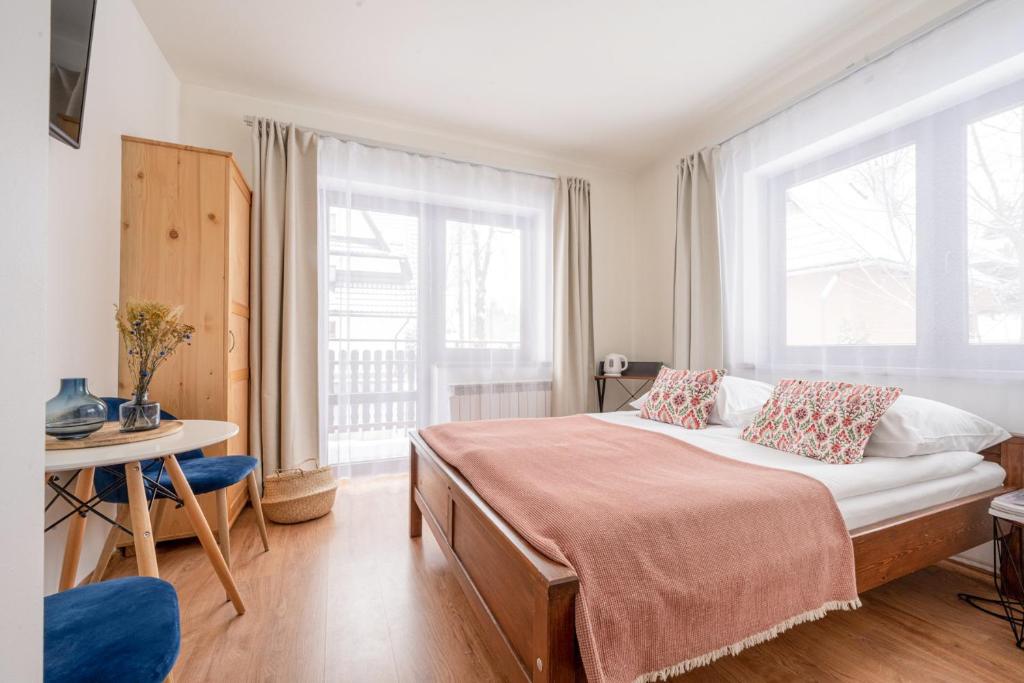 een slaapkamer met een bed, een tafel en 2 ramen bij Pokoje u Kamińskich 26E in Zakopane