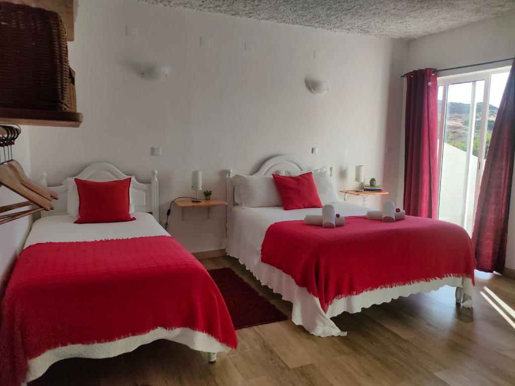 1 dormitorio con 2 camas con colchas rojas y blancas en Vicentina Rooms by Casas do Alentejo en Almograve