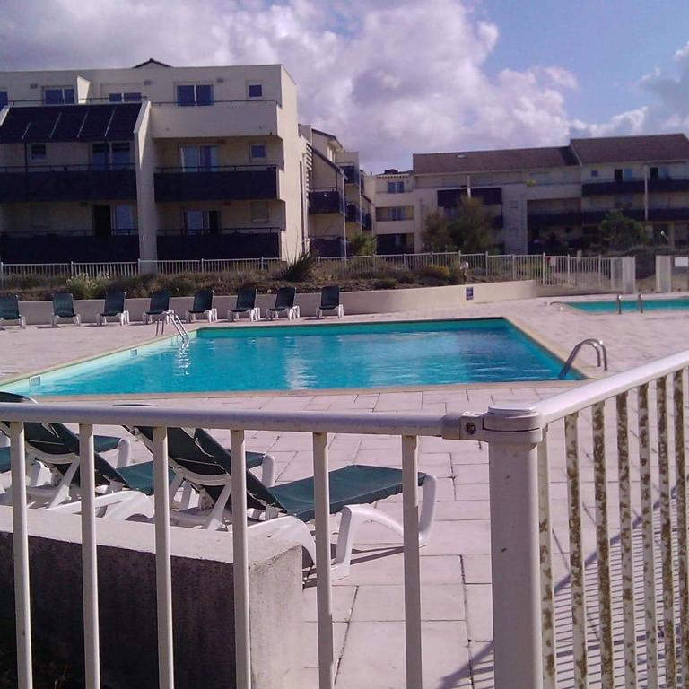 une piscine avec des chaises à côté d'un bâtiment dans l'établissement Lacanau ocean piscine et océan, à Lacanau-Océan