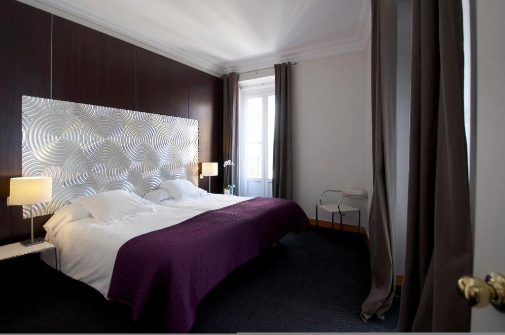 Un dormitorio con una cama grande con una manta morada. en Suite Prado, en Madrid