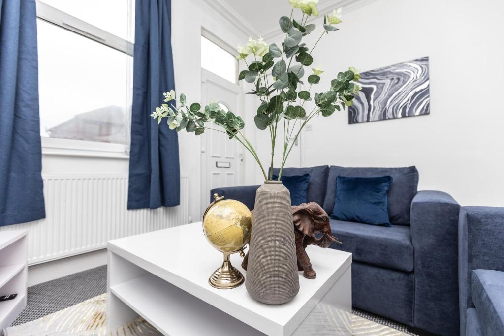 eine Vase mit Blumen auf einem Tisch im Wohnzimmer in der Unterkunft Cosy two bedroom property! in Featherstone