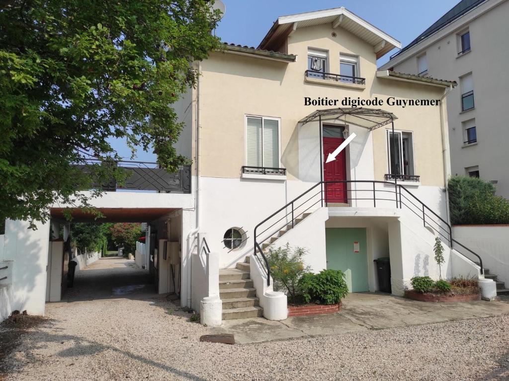 - un bâtiment blanc avec une porte rouge et des escaliers dans l'établissement Guynemer 3 pièces de vie - villa - Terrasse- Clim, à Toulouse