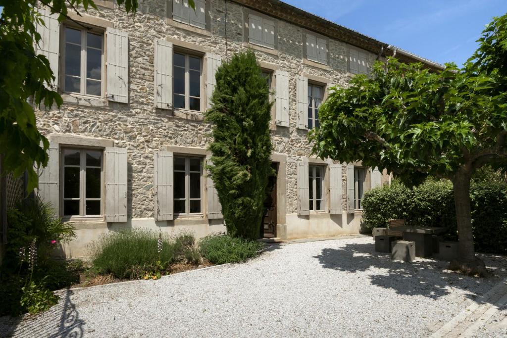 un edificio de piedra con un árbol delante de él en Villa Catharissima, piscine privee, en Blomac