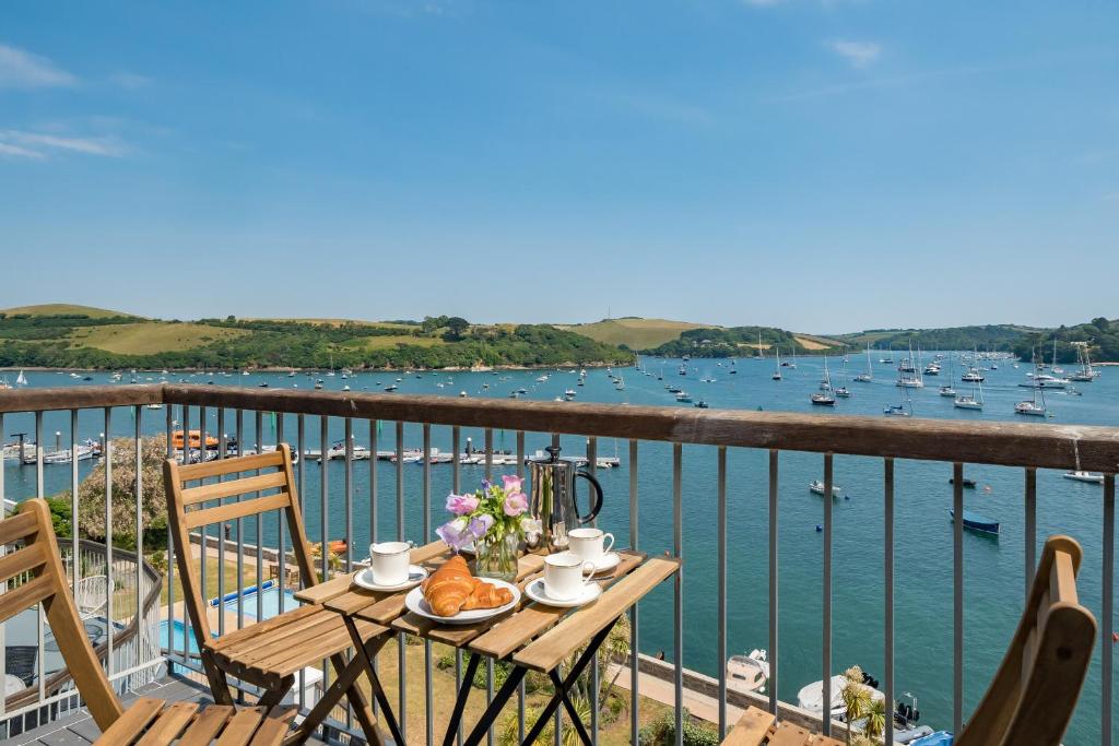 a table with food and flowers on a balcony overlooking the water at N ° 42 The Salcombe in Salcombe