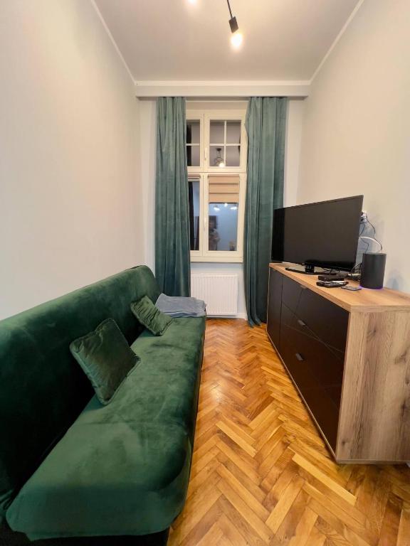 un soggiorno con divano verde e TV di Apartamenty In Centro by 3 maja a Gniezno