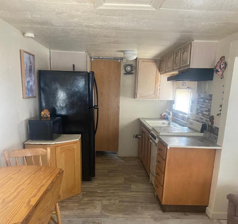 a kitchen with a black refrigerator and wooden cabinets at Park Model Furnished #5 in Tucson
