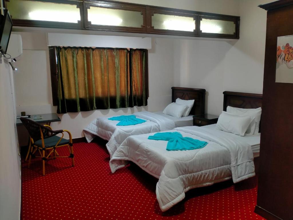 two beds in a room with a red carpet at Hotel luna in Cairo
