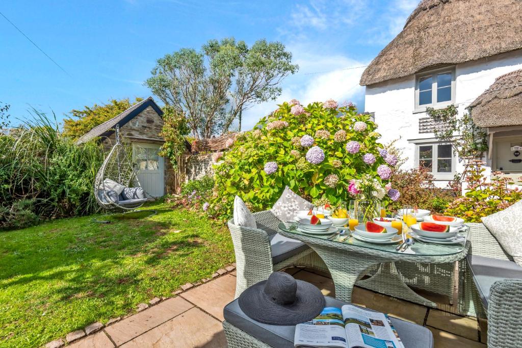 a table and chairs in the garden of a cottage at Tabbs Cottage - Close To Salcombe and Beaches in Malborough