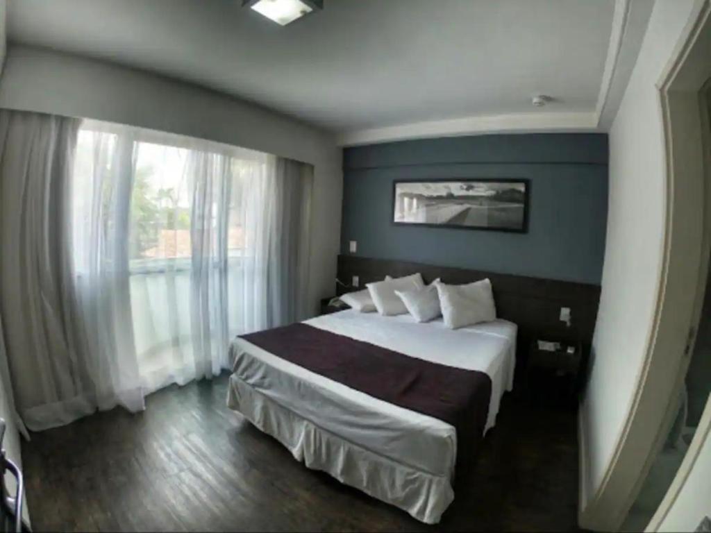 ein Schlafzimmer mit einem großen Bett und einem großen Fenster in der Unterkunft Apartamento Completo ao lado da lagoa da Pampulha in Belo Horizonte