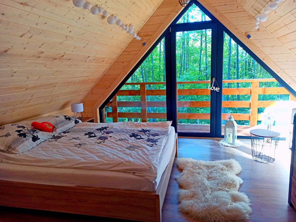 ein Schlafzimmer mit einem Bett in einer Holzhütte in der Unterkunft Las Lorien - wynajem domków letniskowych in Roczyny