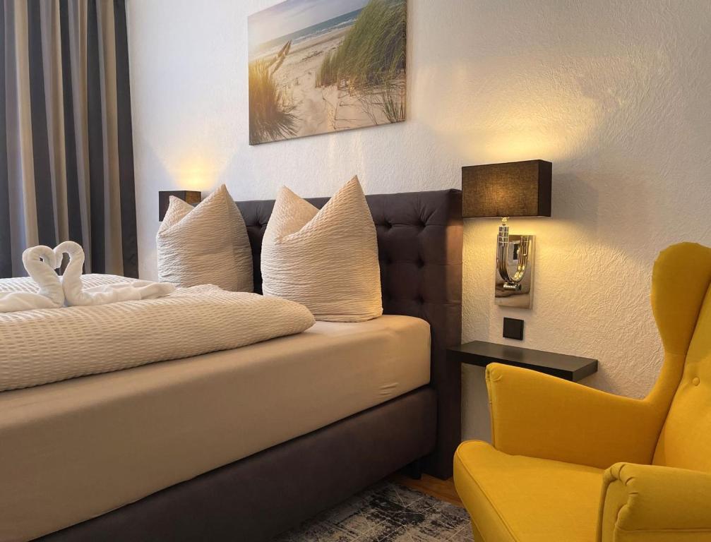 une chambre d'hôtel avec un lit et une chaise jaune dans l'établissement Hotel Antoni, à Bochum