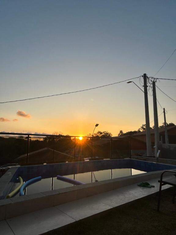 une piscine avec vue sur le coucher du soleil en arrière-plan dans l'établissement Casa condomínio, à Mairinque