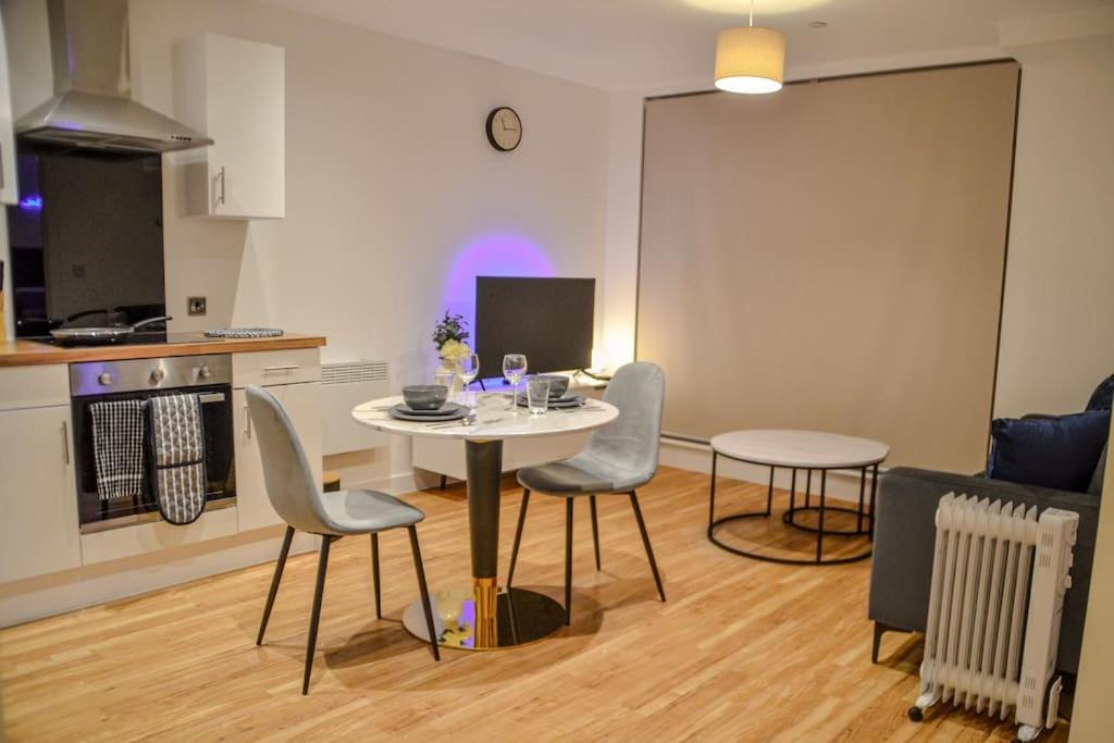 1 bedroom Flat in Manchester في مانشستر: غرفة معيشة مع طاولة وكراسي ومطبخ