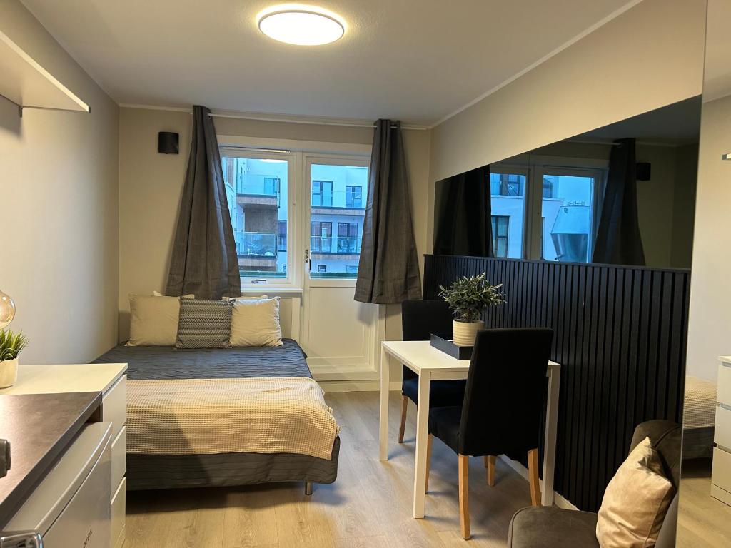 um quarto com uma cama, uma mesa e cadeiras em Skippergata - Rooms em Kristiansand