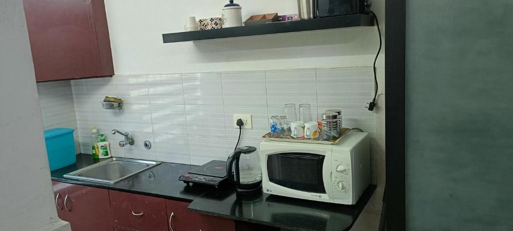 a kitchen counter with a microwave and a sink at Safa Serviced Apartments in Cochin