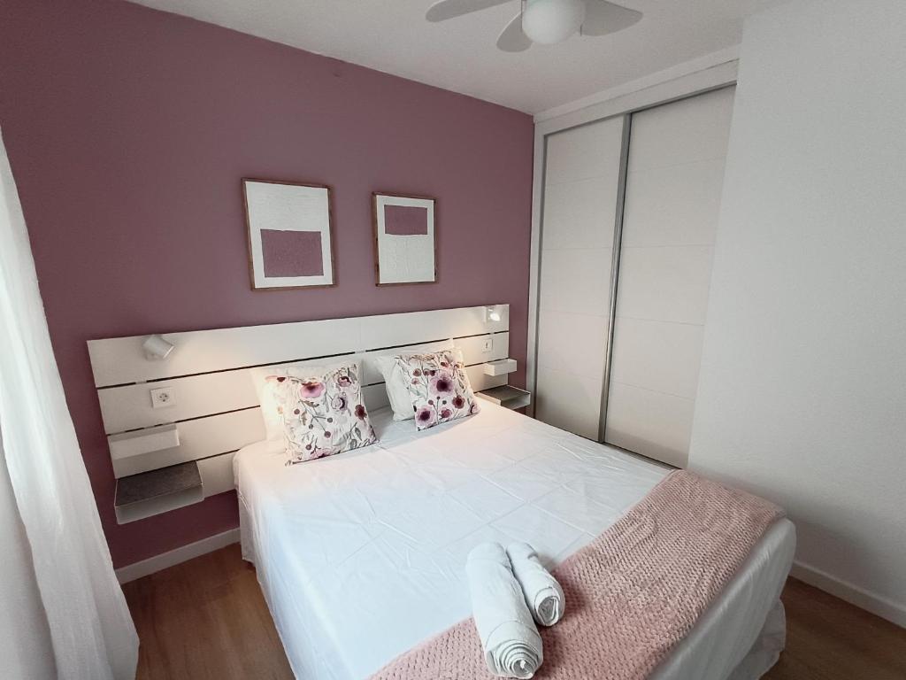 - une chambre avec un lit blanc et un mur violet dans l'établissement Coqueto apto en centro histórico, à Marbella