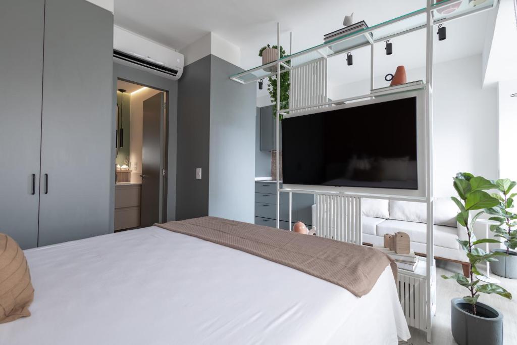a bedroom with a white bed and a flat screen tv at Studio Alto Padrão Brooklin in Sao Paulo