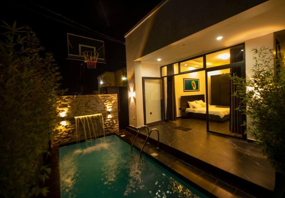 een huis met een zwembad in de nacht met een slaapkamer bij Èze in Kigali