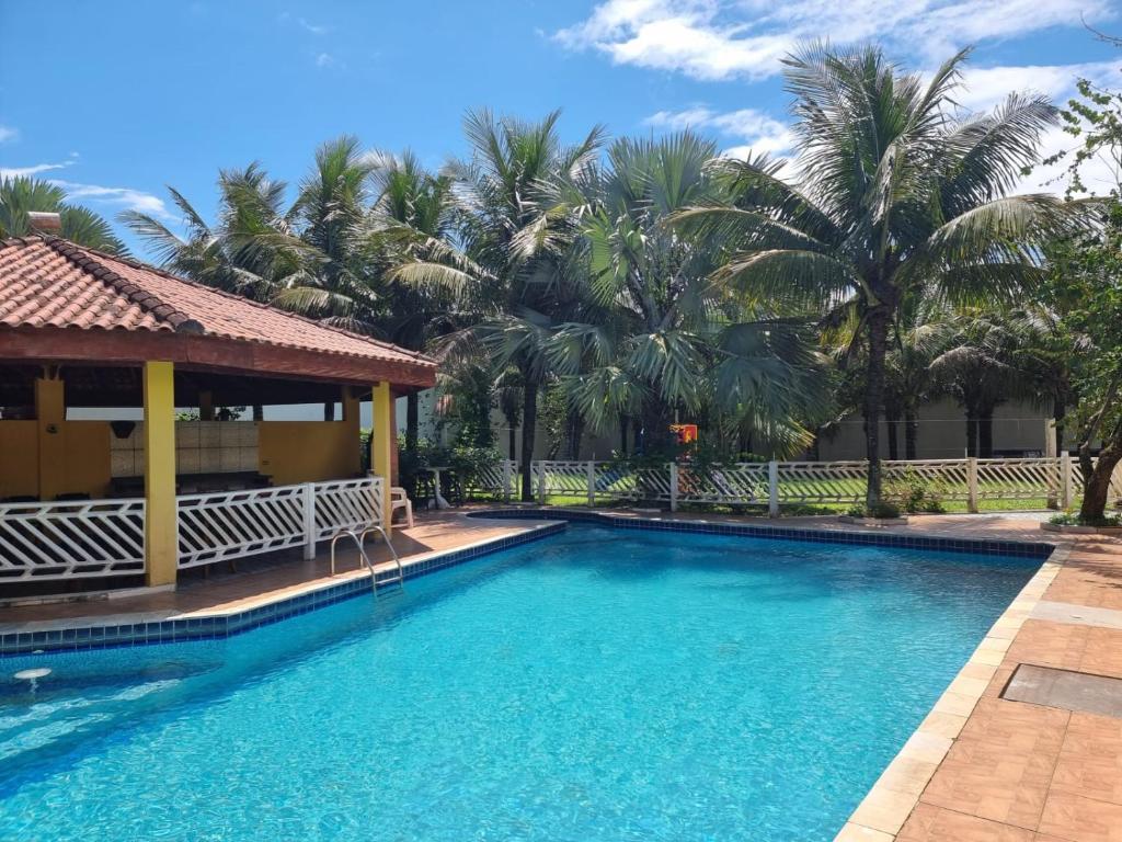 a swimming pool in front of a resort with palm trees at Pousada Ykapê in Ilha Comprida