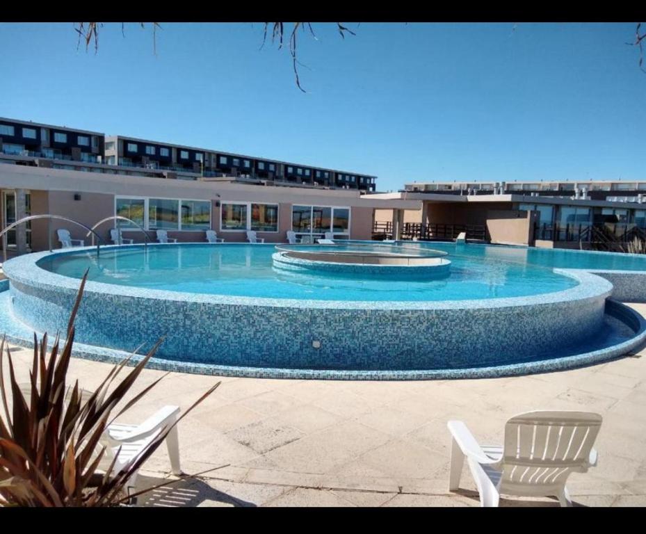 una grande piscina con due sedie e un edificio di Linda Bay Resort y Spa Monoambiente a Mar de las Pampas