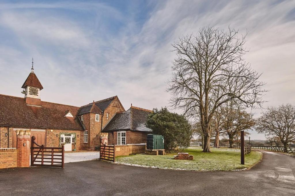 a large brick building with a tree and a church at Stunning Coach House in Sussex in Twineham