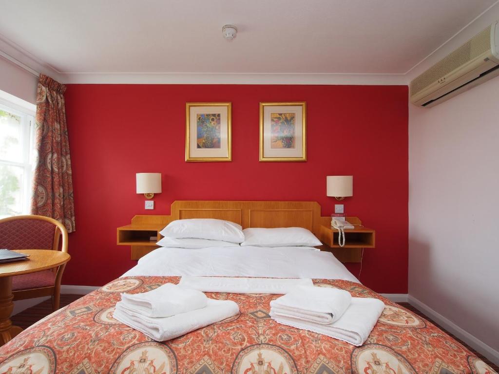 a red bedroom with a large bed with white pillows at The Chatsworth Hotel in Worthing