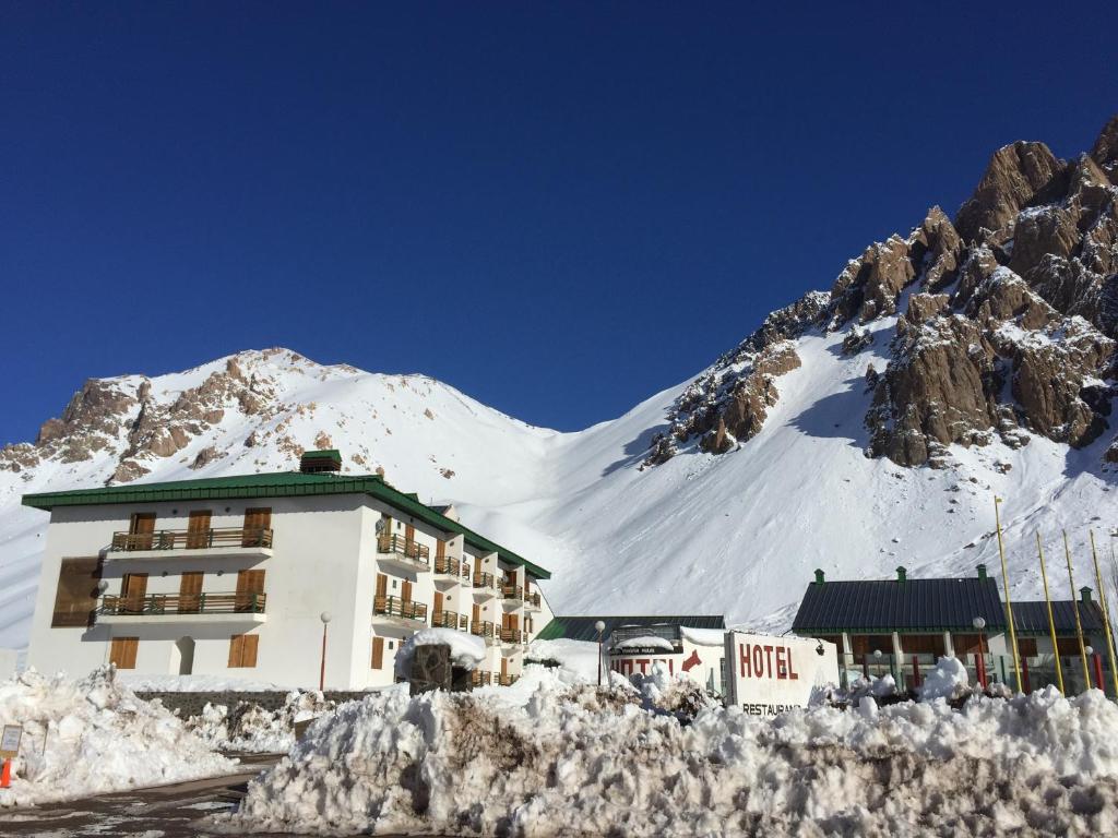 a hotel with a snow covered mountain in the background at Ayelen Hotel de Montana in Los Penitentes