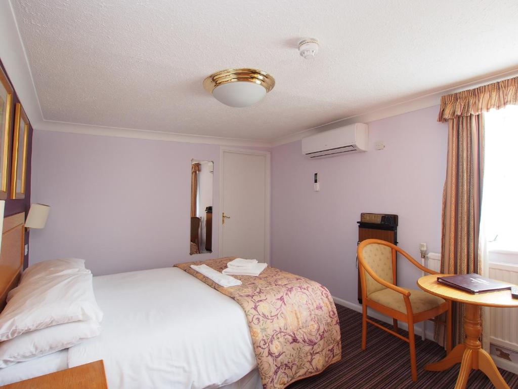 a hotel room with a bed and a table with a laptop at The Chatsworth Hotel in Worthing