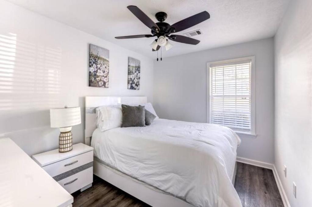 um quarto branco com uma cama e uma ventoinha de tecto em Cheerful 3 bedroom house with patio em Auburn