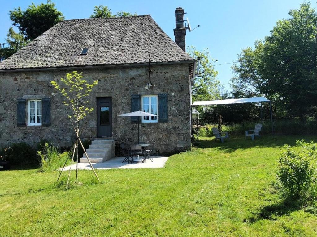 ein altes Steinhaus mit einem Tisch und einem Sonnenschirm in der Unterkunft Gîte de France La maisonnette 2 épis - Gîte de France 2 personnes 764 in Servières-le-Château