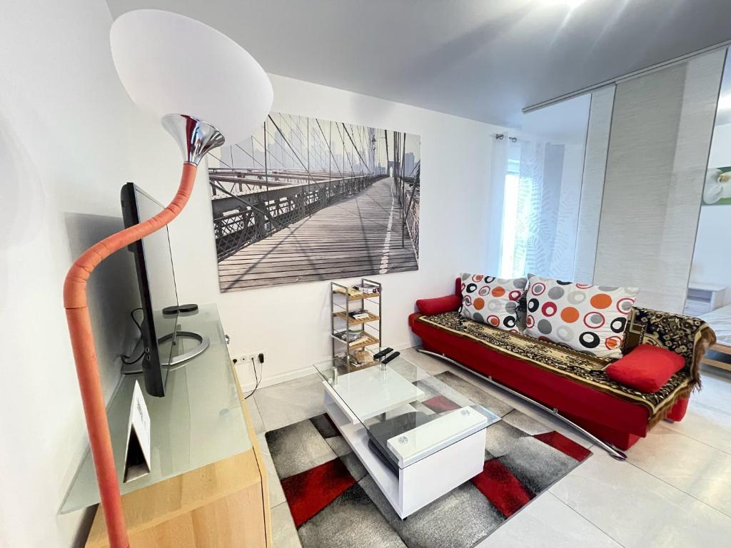 uma sala de estar com um sofá vermelho e uma mesa em nuovo appartamento saint louis 68300 tra francia e svizzera em Saint-Louis