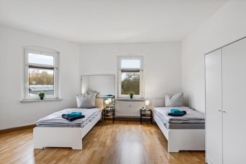 - un salon blanc avec 2 lits et un bureau dans l'établissement YourFavoriteBed - Moderne Monteurwohnungen in Zwickau, à Zwickau