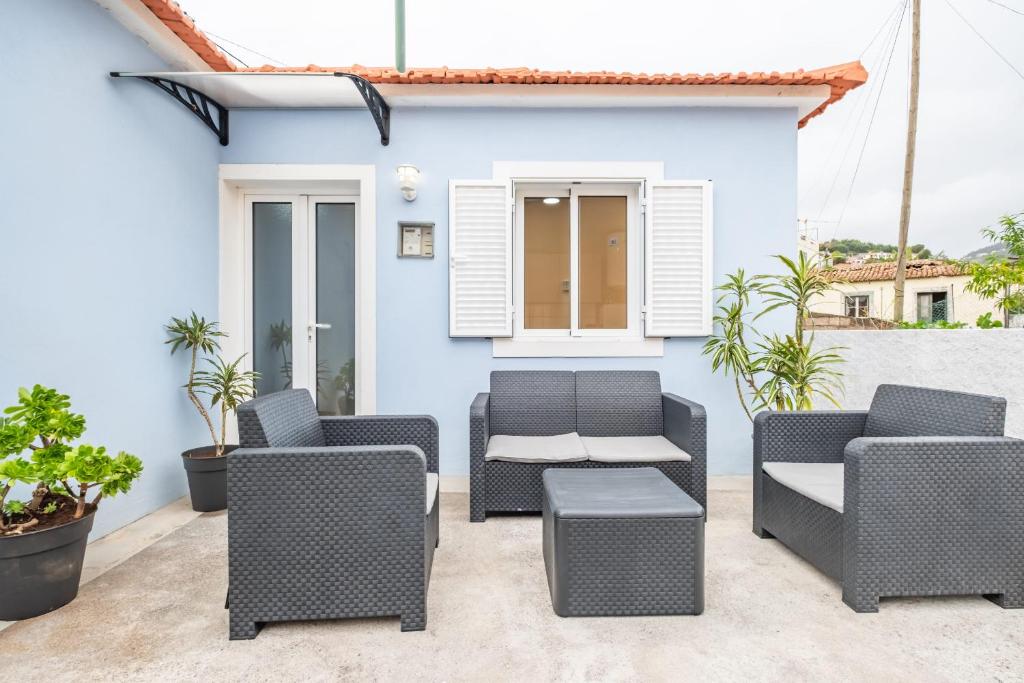 un patio con muebles de mimbre frente a una pared azul en The Blue House en Funchal