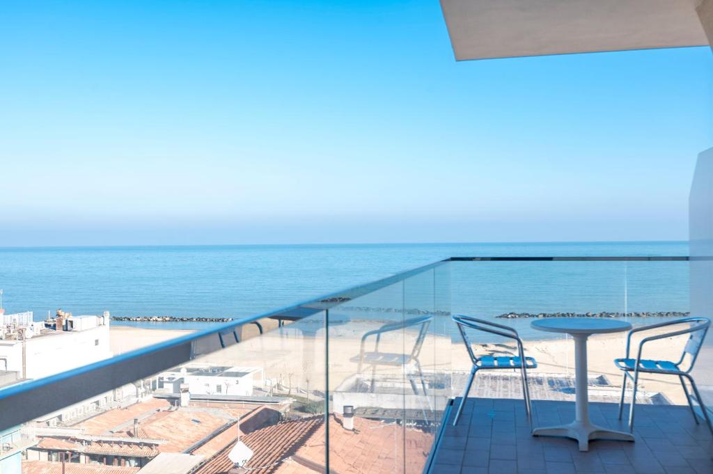 balcón con mesa, sillas y vistas al océano en Hotel Harmony, en Rímini