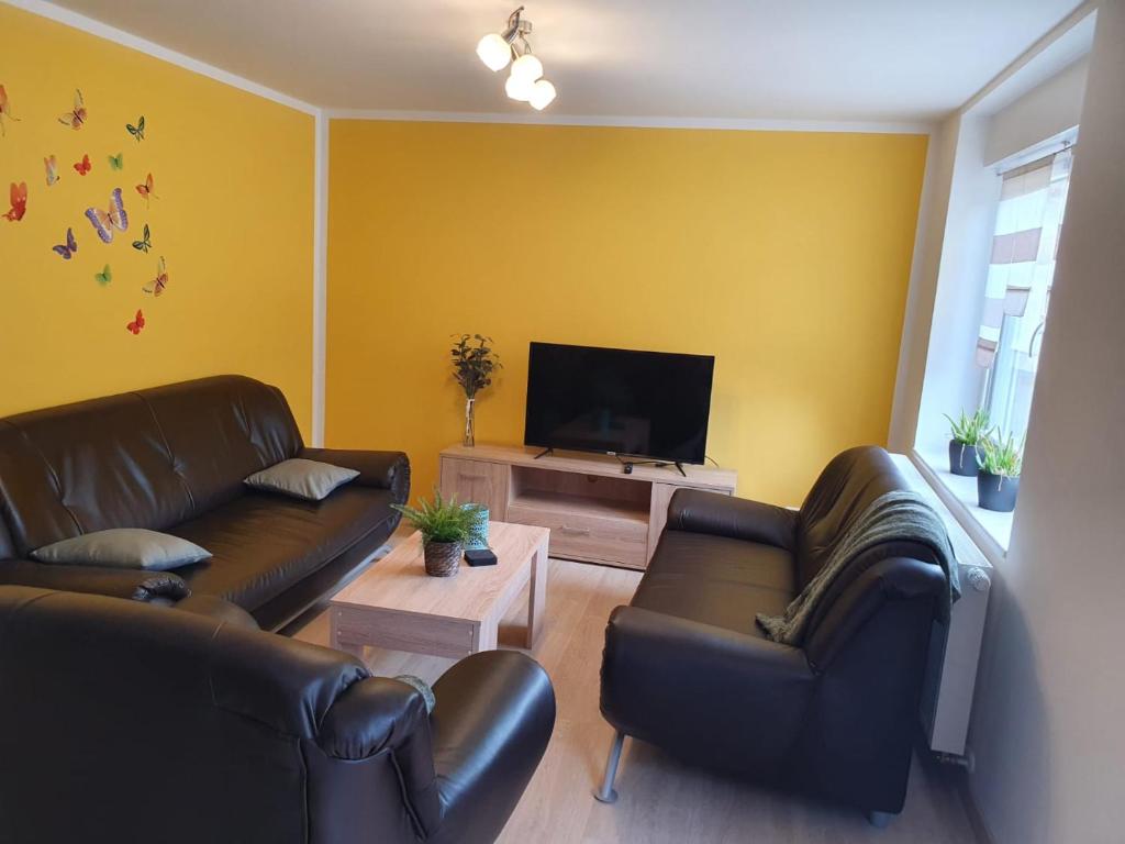 a living room with two leather couches and a flat screen tv at Ferienwohnung am Wald 