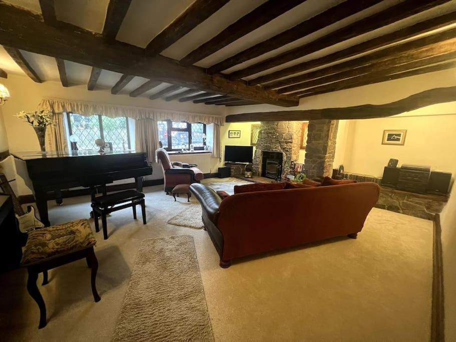 a living room with a couch and a piano at Grace Dieu Cottage - Sleeps 7 in Whitwick