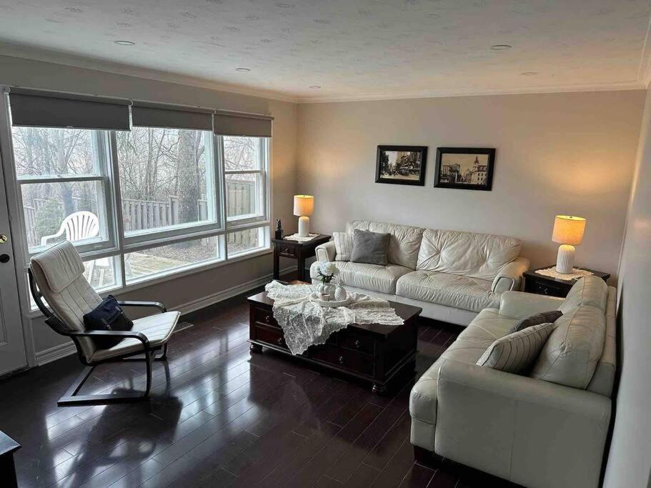 uma sala de estar com um sofá, uma mesa e cadeiras em Enjoy luxury living em Mississauga